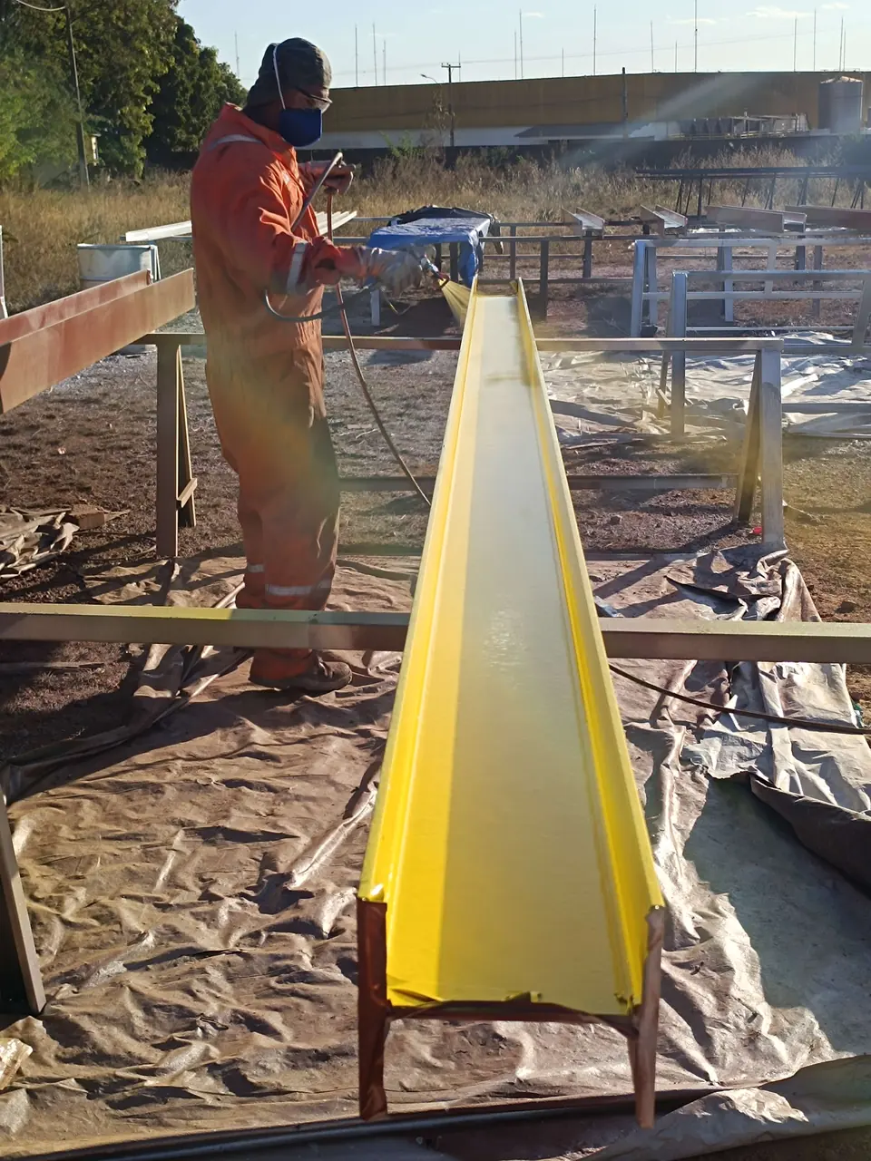 Pintor aplicando acabamento amarelo em viga
